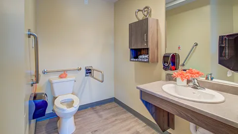Bathroom with a sink, toilet and grab rails.