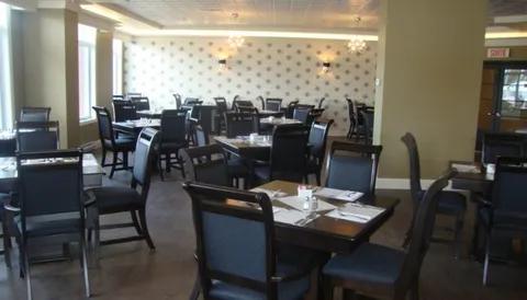 Dining room with dark tables and chairs beside tall windows