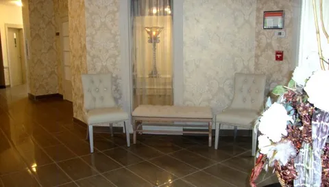 Two cream chairs and a bench beside a glass display cabinet