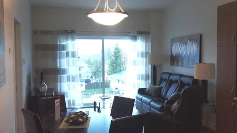 Sitting area with a dark leather sofa, glass table and sliding patio doors