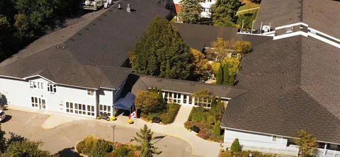 Aerial view of a white residence building beside trees and lawns