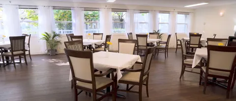 Dining room with white tablecloths, wooden chairs and tall windows