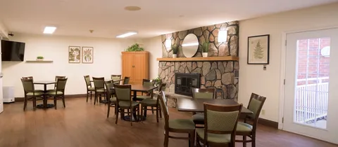 Tables and upholstered chairs beside a stone fireplace