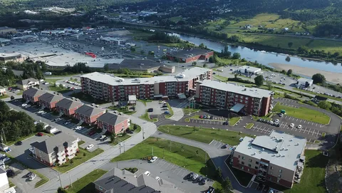 Aerial view of residence buildings, parking areas and lawns beside a river