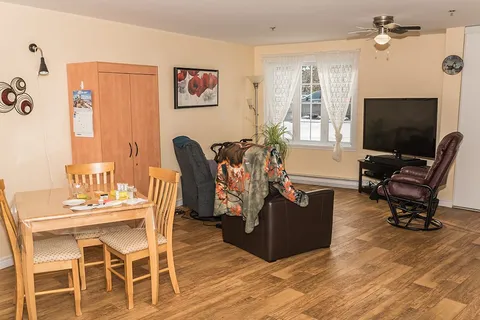 Room with a dining table, armchairs, a wooden wardrobe and television