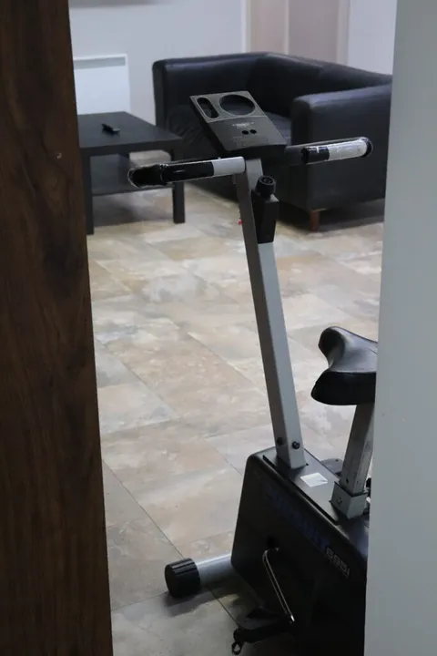 Exercise bicycle in a room with a black armchair and tiled flooring