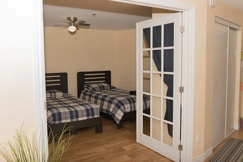 Bedroom with two single beds and checked bedspreads behind glass doors