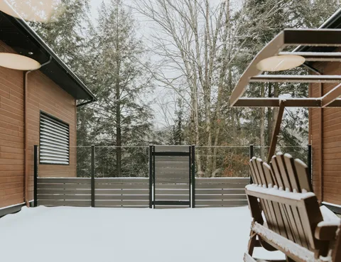 Covered wooden deck with benches, railings and trees beyond