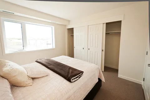 Bedroom with a double bed, a window and closet doors.