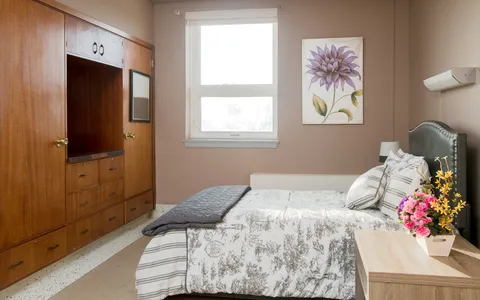 Bedroom with a bed, fitted wood cabinets and a large window.