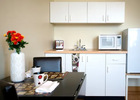 Suite kitchenette with white cabinets, a microwave and a small dining table.