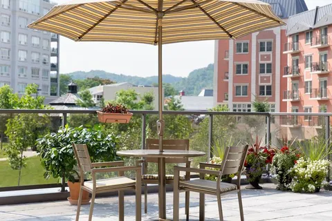 Rooftop patio with a table, chairs, umbrella and potted plants.