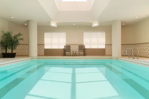 Indoor swimming pool with large shaded windows.