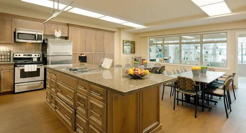 Craft kitchen with an island, appliances and a long table.