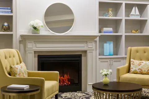 Lobby seating beside a fireplace, shelves and wall mirror.