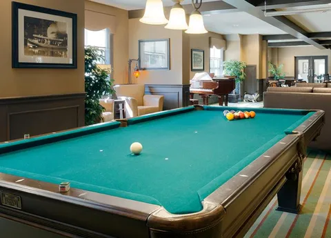 Pool table beside lounge seating and a piano.