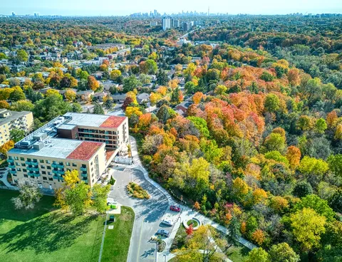 Aerial view of a residence with a curved driveway, parking spaces and autumn trees