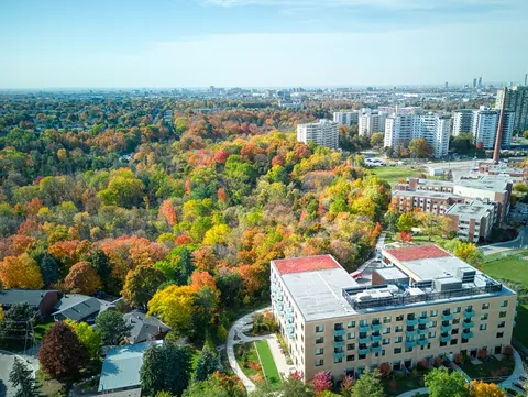 Aerial view of a residence with balconies beside woodland in autumn