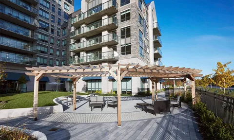 Outdoor seating beneath a wooden pergola beside the residence