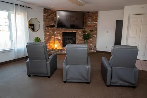 Television area with recliners and a brick fireplace.