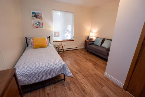 Bedroom with a bed, sofa and bedside lamp.
