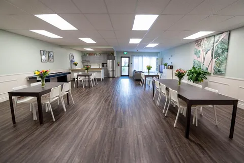 Activity room with tables, chairs and wall artwork.