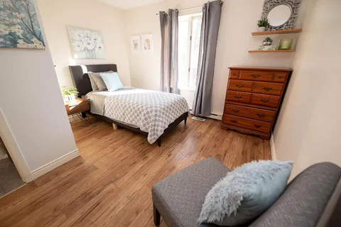 Bedroom with a single bed, dresser, armchair and window.