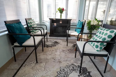 Sunroom with upholstered chairs and large windows.