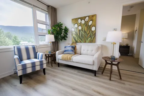 Sitting area with a white sofa, striped armchair and floral artwork