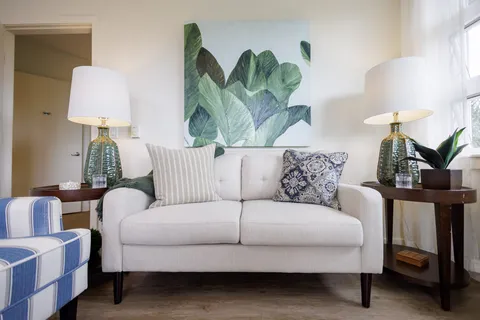 Sitting area with a white sofa, striped chair and large green leaf artwork