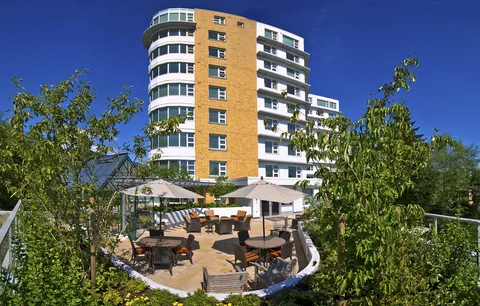 Tall residence with balconies overlooking a patio and planted gardens