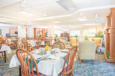 Dining room with set tables, wooden chairs and a fireplace seating area.