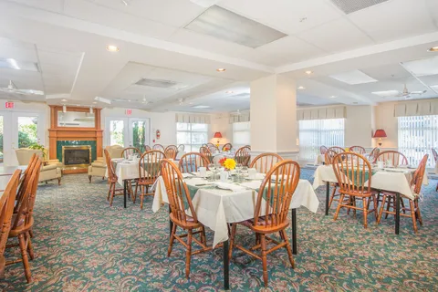 Dining room with round tables, wooden chairs and broad windows.
