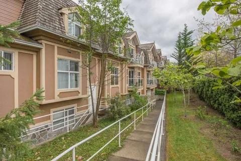 Side of the residence beside a planted path and access ramp.