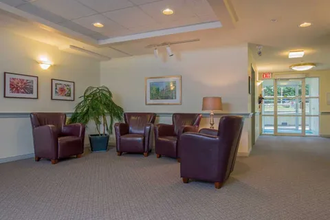 Entrance lounge with armchairs, plants and glazed doors.