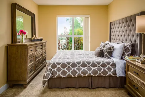 Bedroom with a tufted headboard, bedside table and mirrored dresser