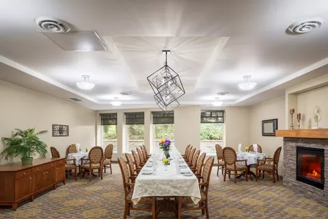 Long dining table beneath pendant lights beside a fireplace