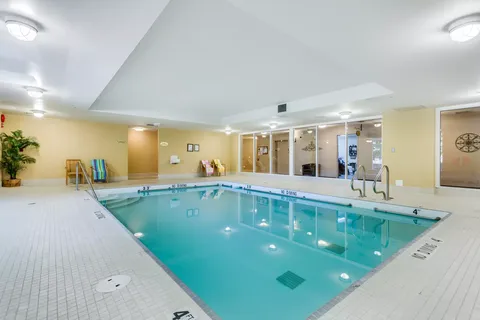 Indoor swimming pool with tiled surround and glass partitions