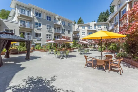 Residence buildings surround a paved courtyard with patio tables and umbrellas