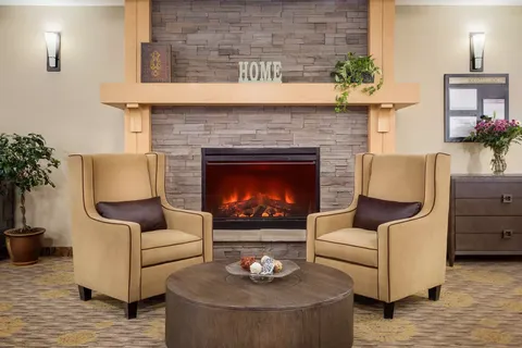 Two armchairs beside a stone fireplace and a round coffee table