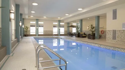 Indoor swimming pool with a metal handrail and tiled deck