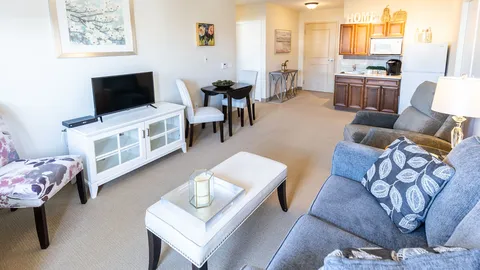 Sitting area with a blue sofa, television, dining table and kitchenette