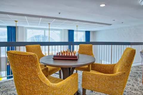 Seating nook with a chess table and upholstered chairs.