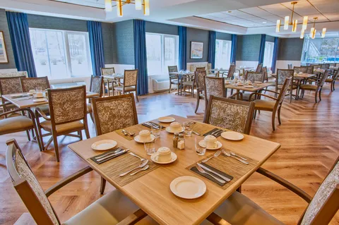 Dining room with set tables, wooden chairs and windows.