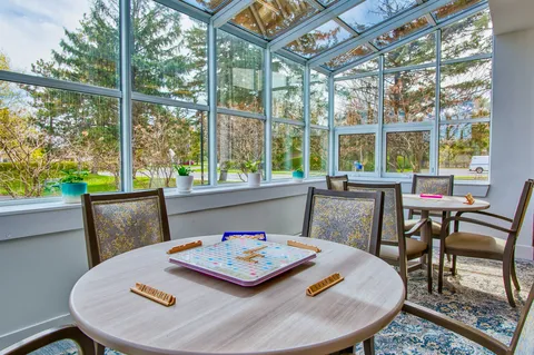 Glazed sunroom with tables, chairs and garden views.