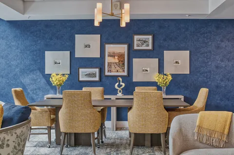 Reading area with a long table, chairs and framed artwork.