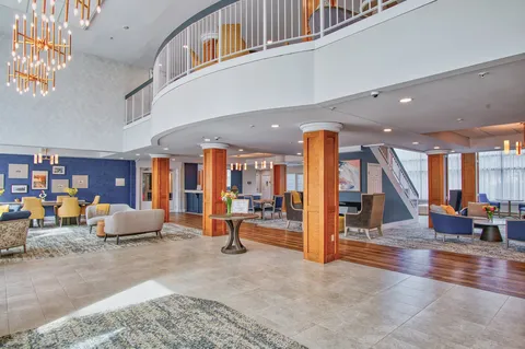 Entrance lobby with a curved balcony, reception counter and seating.
