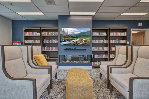 Theatre with upholstered chairs and a large television.