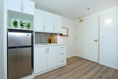 Suite kitchenette with white cabinets and a refrigerator