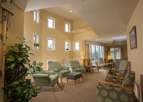 Common lounge with tall windows, armchairs and a high ceiling.
